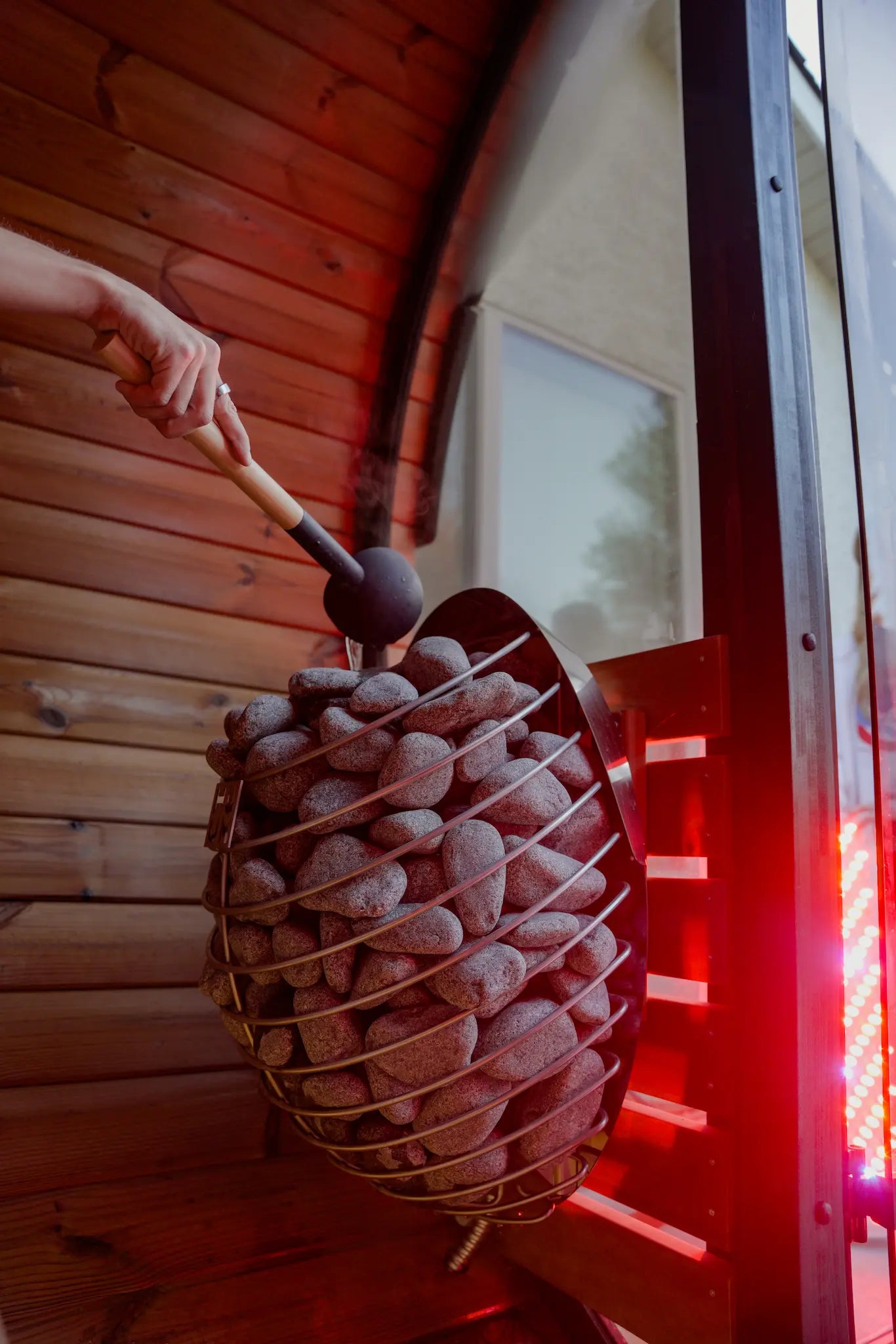 Person carrying wooden slats outdoors with trees and a building in the background.
