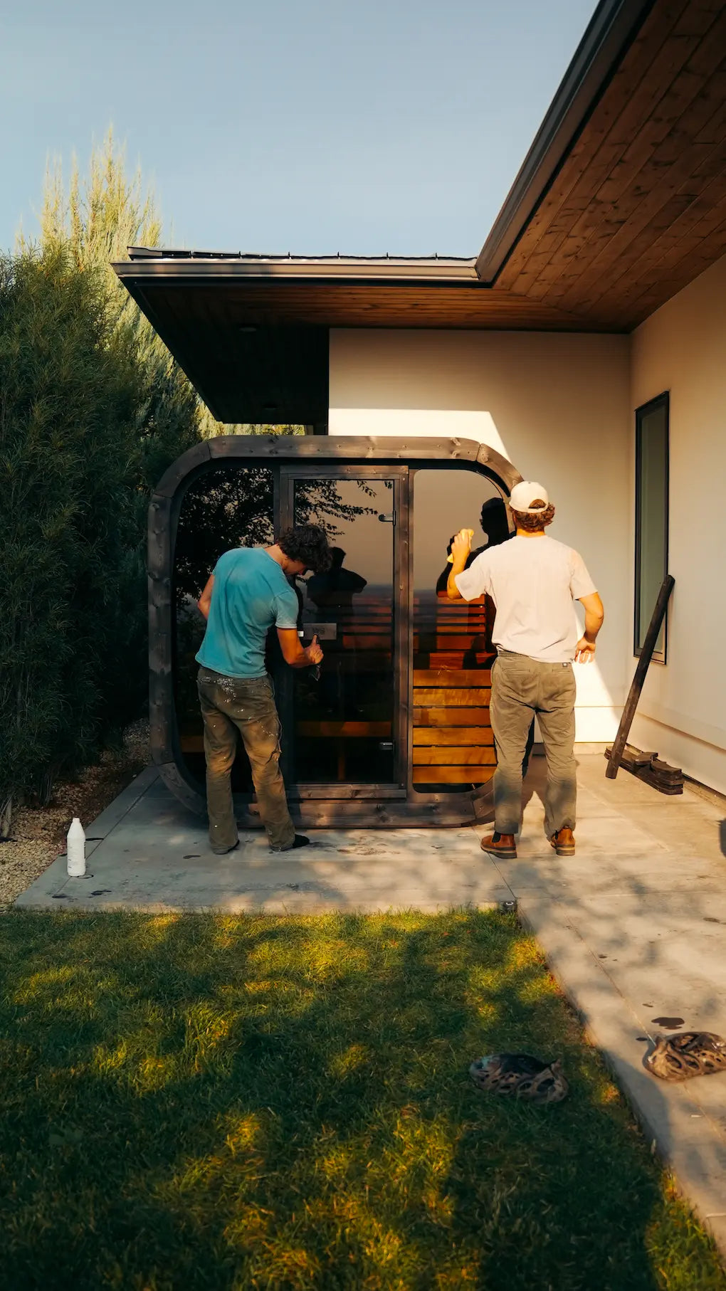 Person carrying wooden slats outdoors with trees and a building in the background.